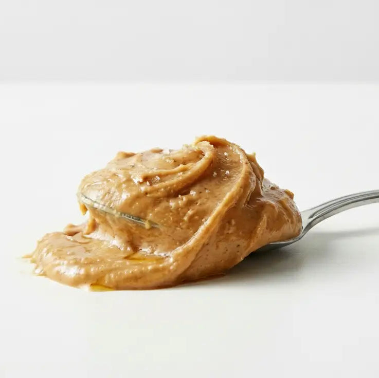 Peanut butter on a metal spoon on a white table