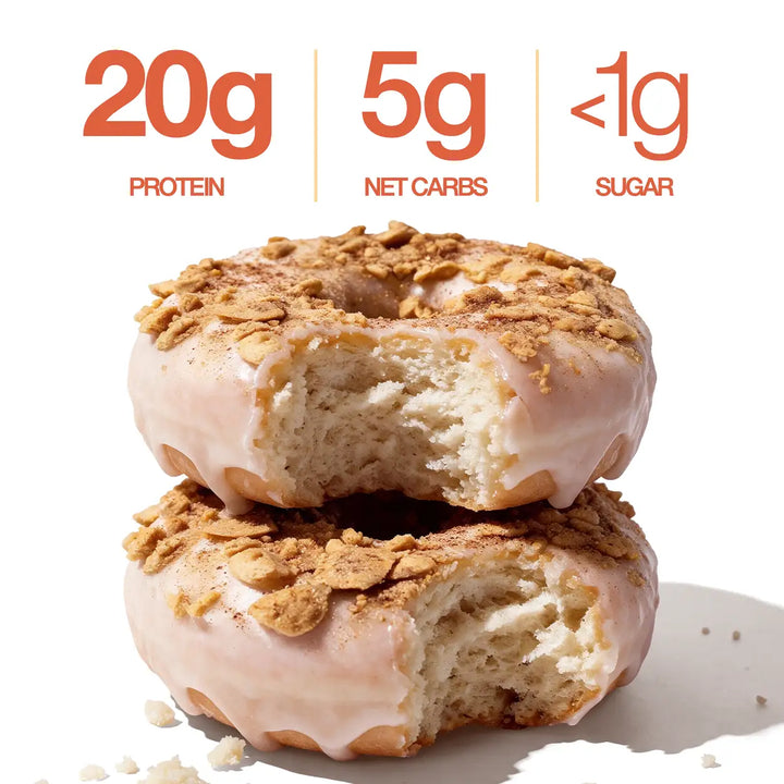 Two glazed Cinnamon Crumble Mini Protein Donuts with bites revealing the interior, highlighting 20g protein, 5g net carbs, and less than 1g sugar per serving.
