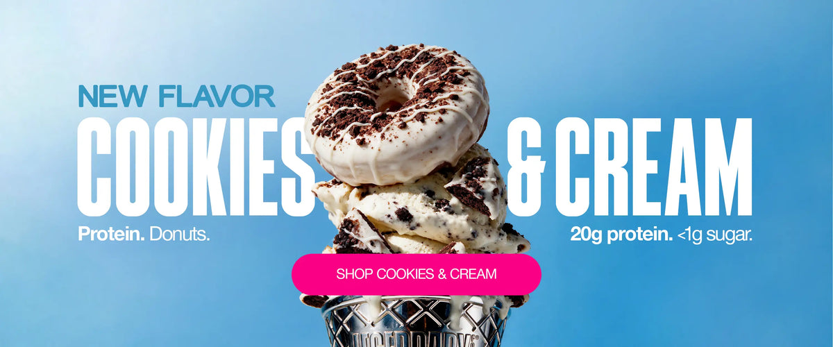 Cookies & Cream Legendary Protein Donuts topped with white icing, chocolate cookie crumbles and drizzle, stacked over cookies-and-cream ice cream. Text reads “New Flavor Cookies & Cream,” “20g protein,” and “<1g sugar.”