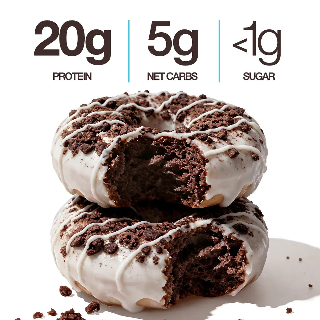 Two Cookies & Cream Mini Protein Donuts with white icing, chocolate cookie crumbles and white drizzle, shown with 20g protein, 5g net carbs and less than 1g sugar callouts.