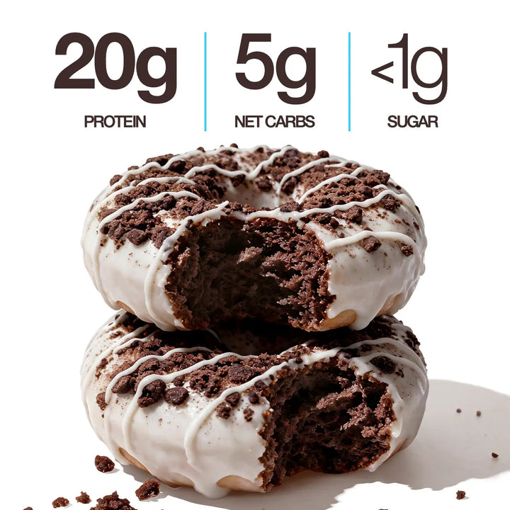 Two Cookies & Cream Mini Protein Donuts with white icing, chocolate cookie crumbles and white drizzle, shown with 20g protein, 5g net carbs and less than 1g sugar callouts.