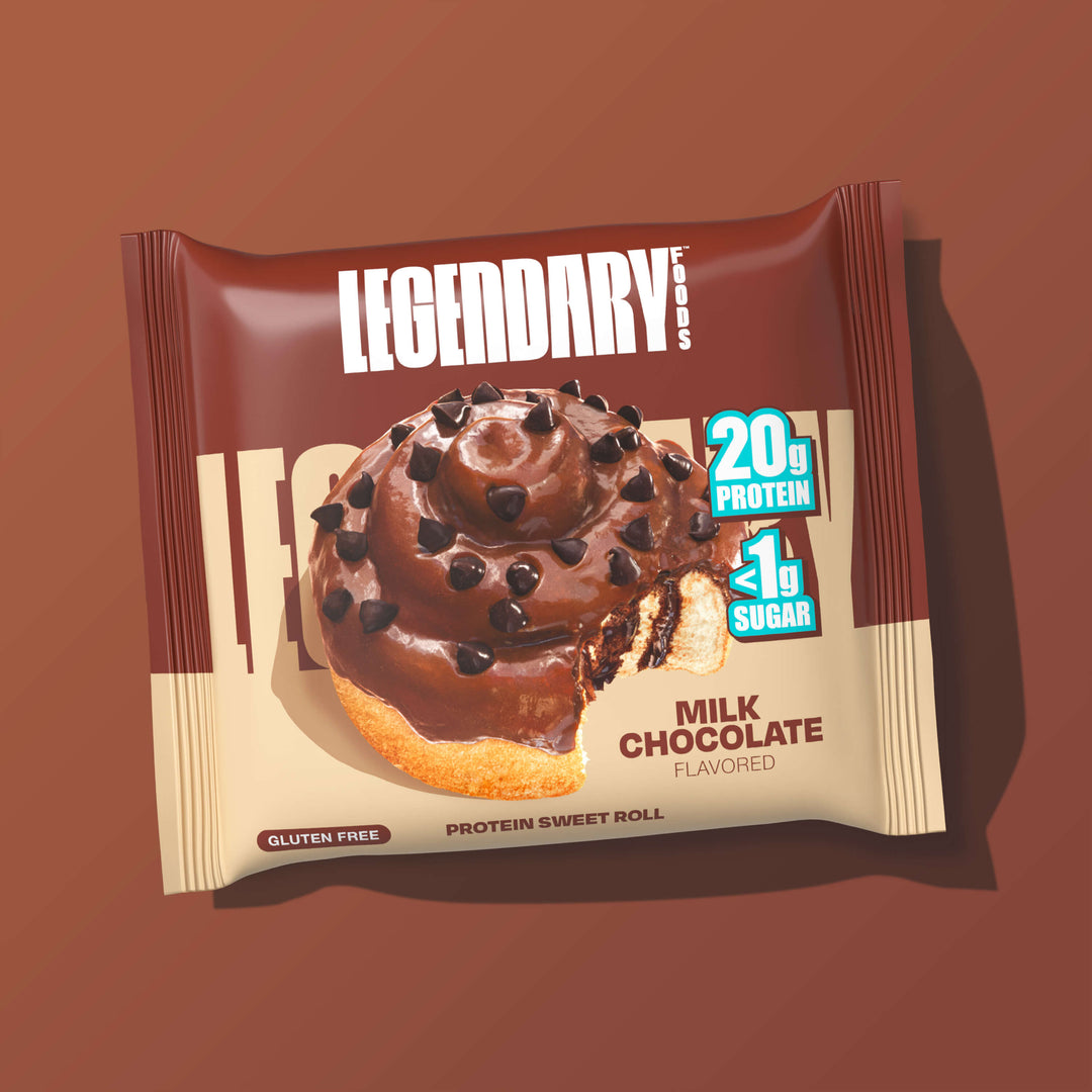 A single wrapped Milk Chocolate Protein Sweet Roll is shown on a rich brown background. The packaging features the Legendary Foods logo, an image of the roll with a bite taken out, and callouts for "20g Protein" and "<1g Sugar". Product is labeled as Gluten Free and Protein Sweet Roll.