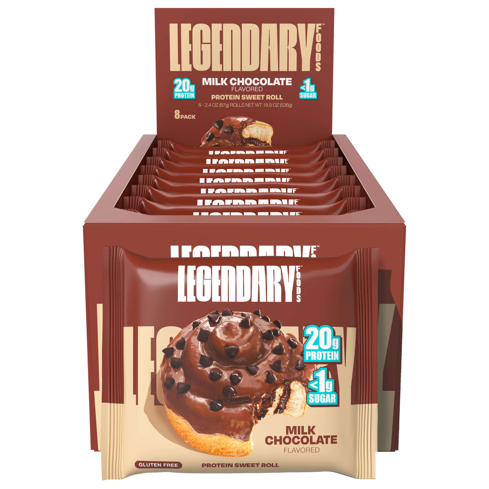 An open retail display box of Legendary Foods Milk Chocolate Protein Sweet Rolls. Multiple individual packages are neatly arranged in the box, each showing the same visual branding—chocolate frosted roll with chocolate chips and a bite missing, alongside “20g Protein” and “<1g Sugar” labels.