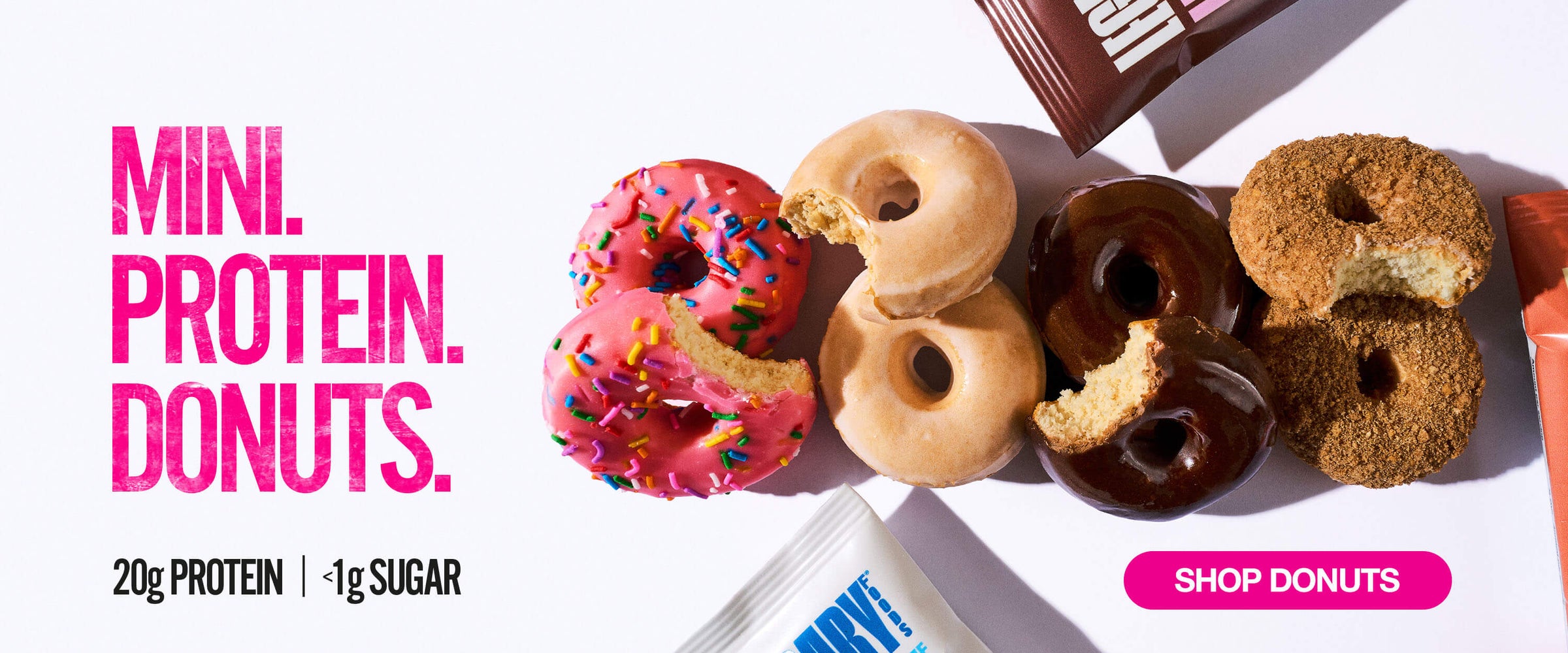 Protein mini donuts in pink, vanilla, chocolate, and cinnamon flavors with bites shown; text reads “Mini Protein Donuts, 20g protein, <1g sugar”