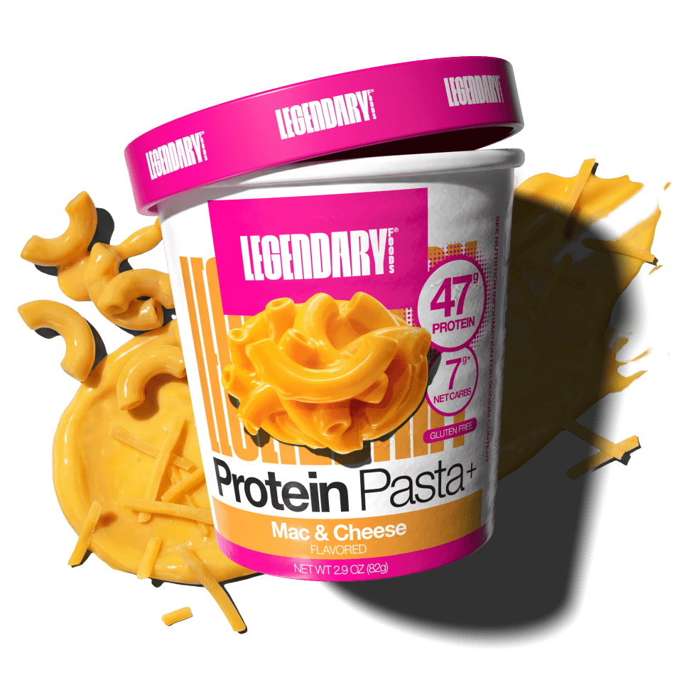 Angled cup of Protein Pasta Mac & Cheese with cheddar cheese and noodles in the background
