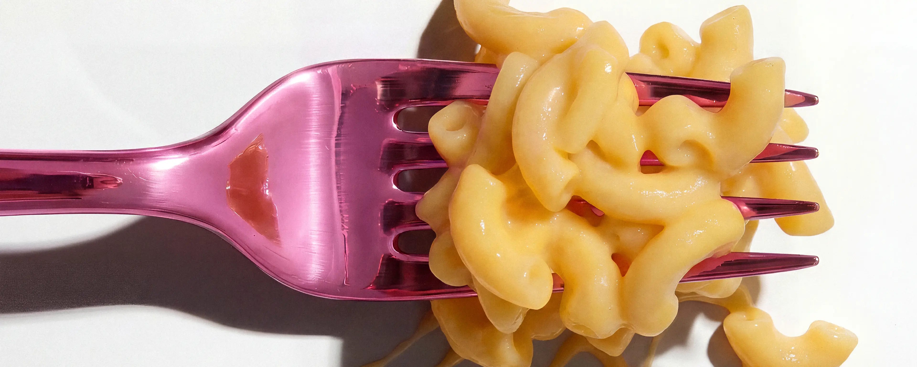Macaroni and cheese on a pink fork against a white background