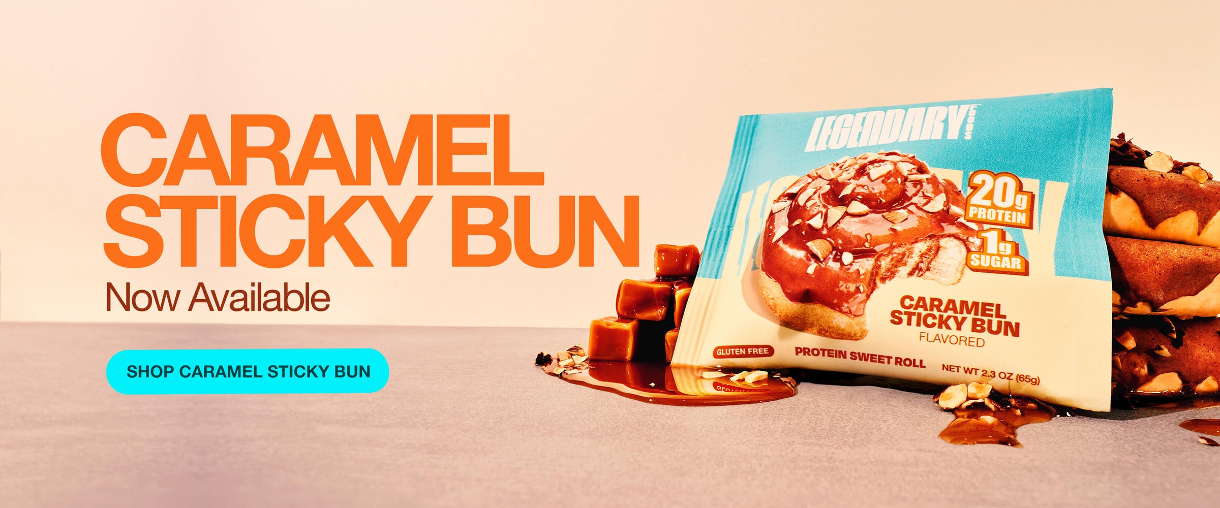 Protein caramel sticky bun in packaging with caramel cubes and nuts. Bold text announces 'Caramel Sticky Bun Now Available' with a shop button.