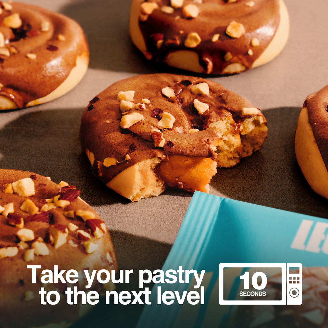 Caramel Sticky Bun protein pastries on a table, one bitten, with text: 'Take your pastry to the next level, 10 seconds in microwave'.